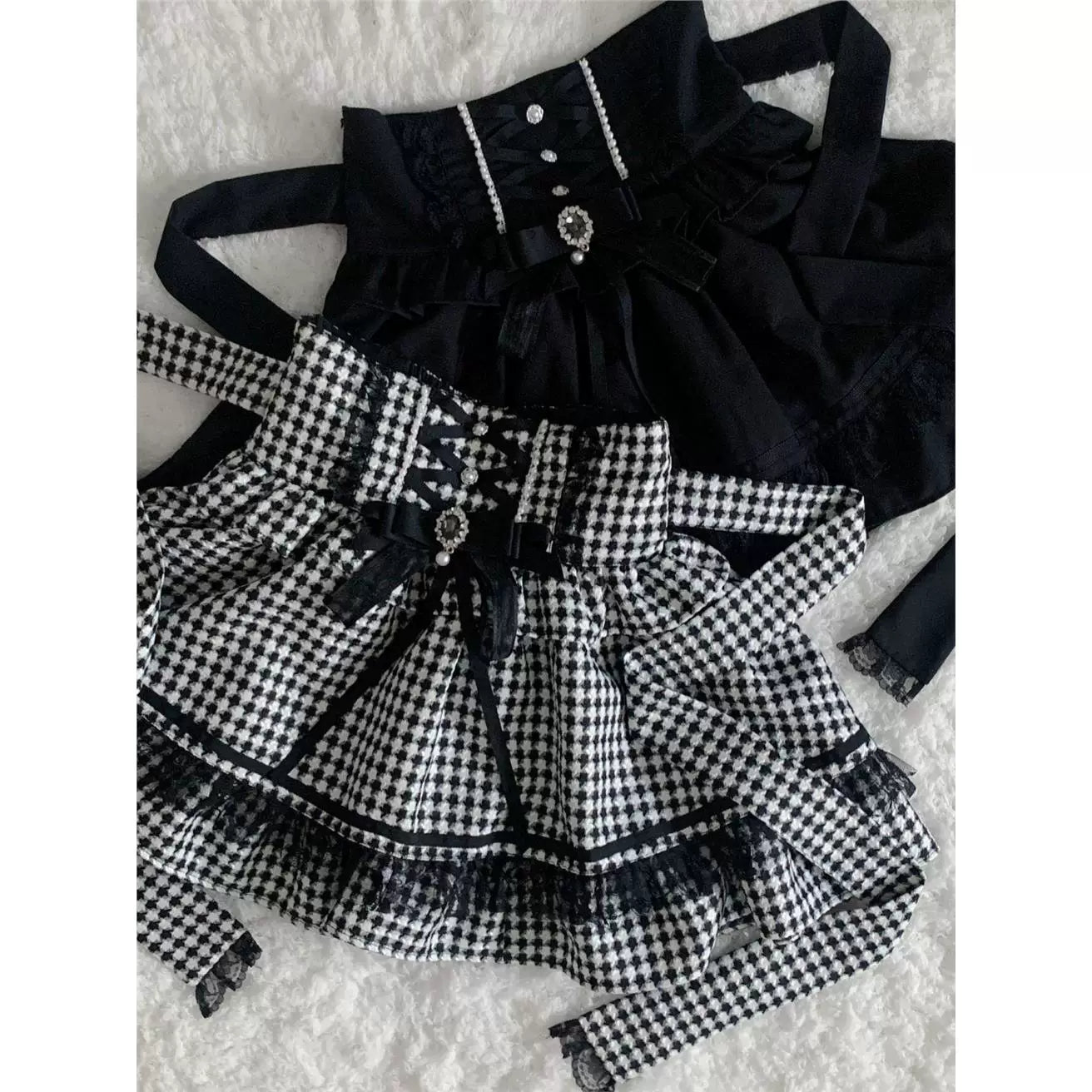 Black and houndstooth skirts with included bows and lace trim laid flat