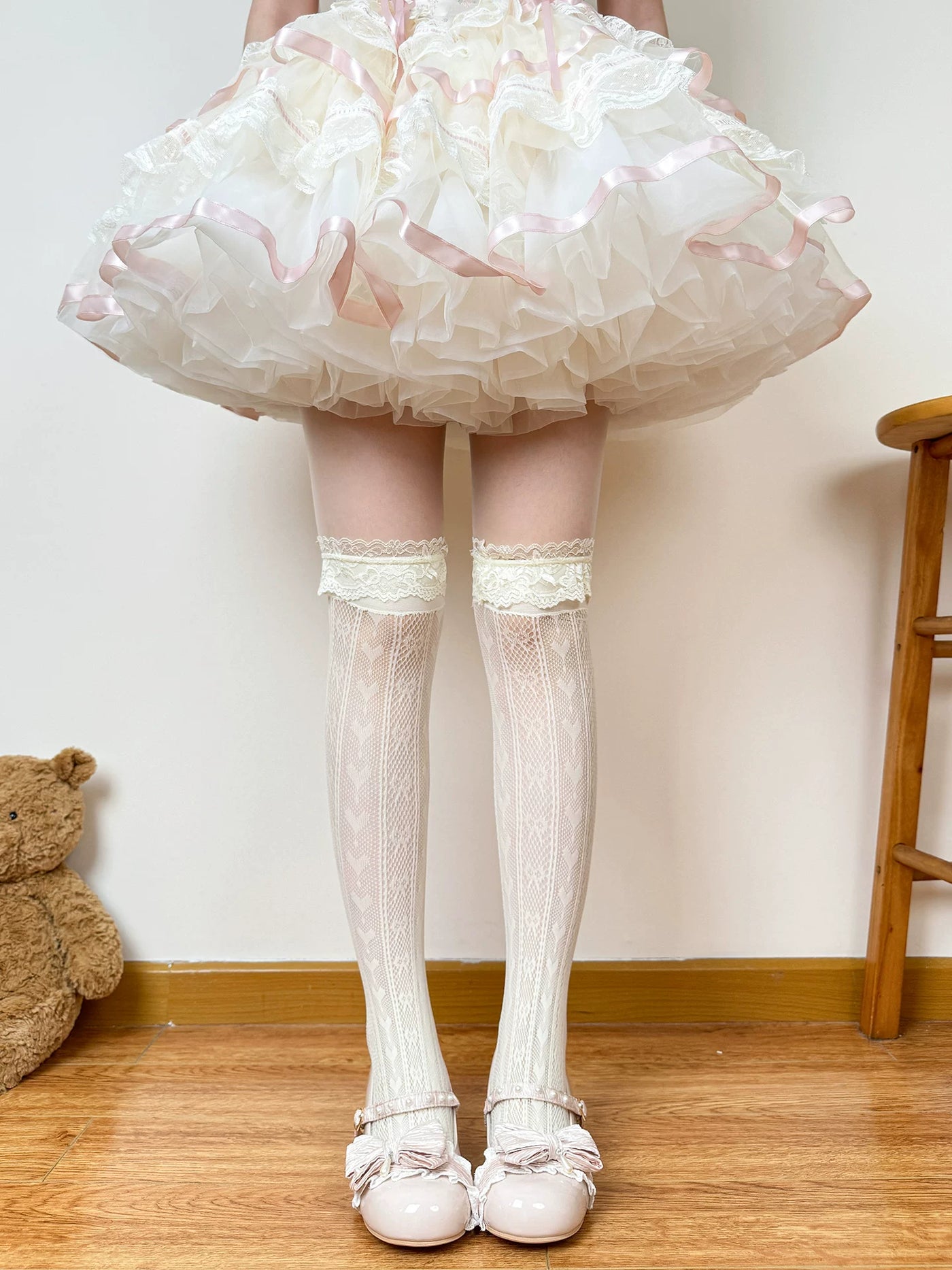 Milky-yellow lace-trimmed slouch socks with ribbon bows worn with a frilled skirt.