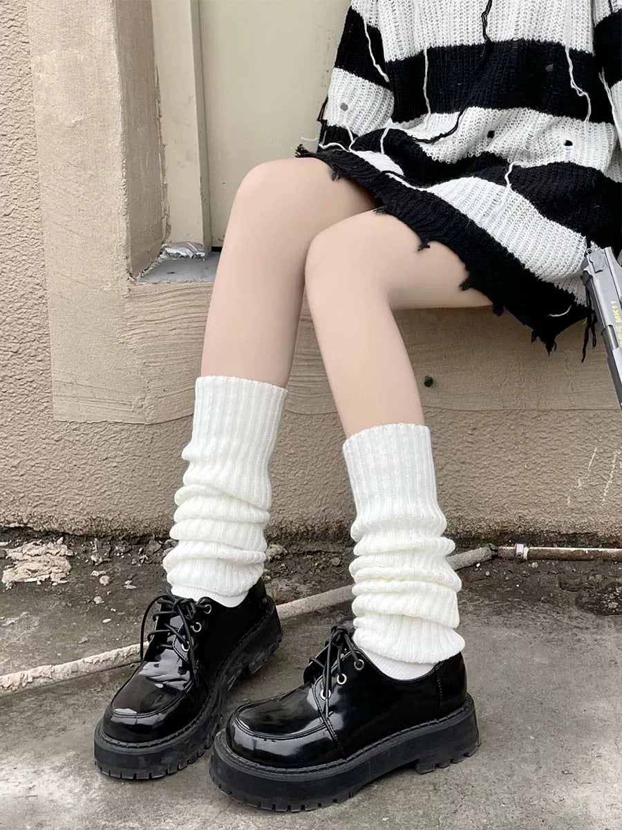Milky-white ribbed knit leg warmers gathered above black platform shoes