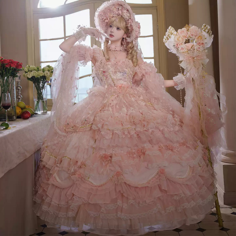 Model wearing an ornate blush-pink Lolita JSK with tiered ruffles in a classical interior.