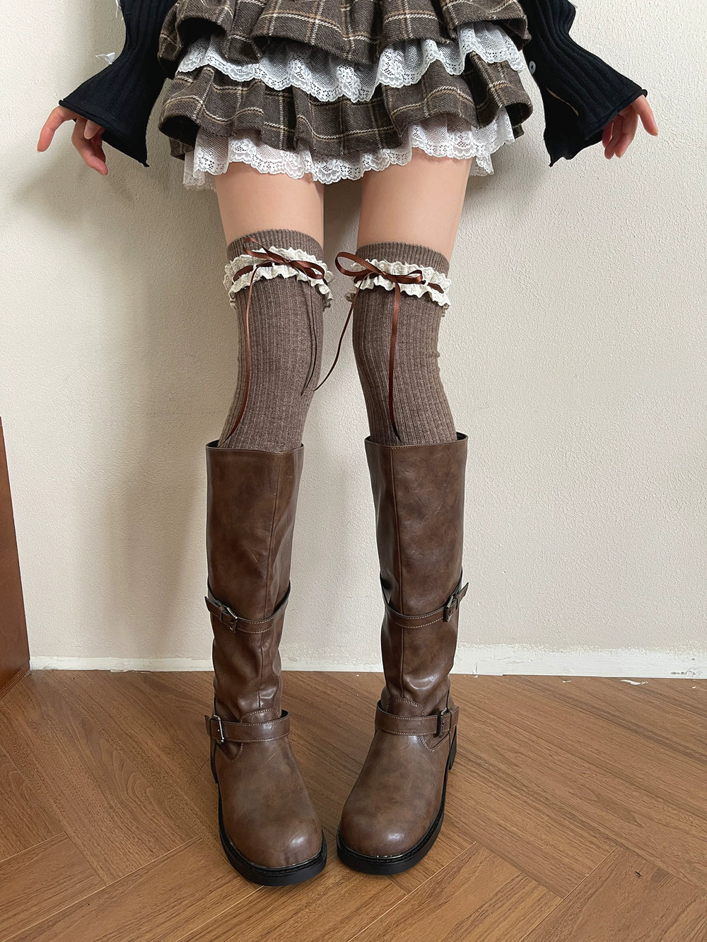 Brown over-the-knee socks with lace trim and ribbon ties styled with tall boots.
