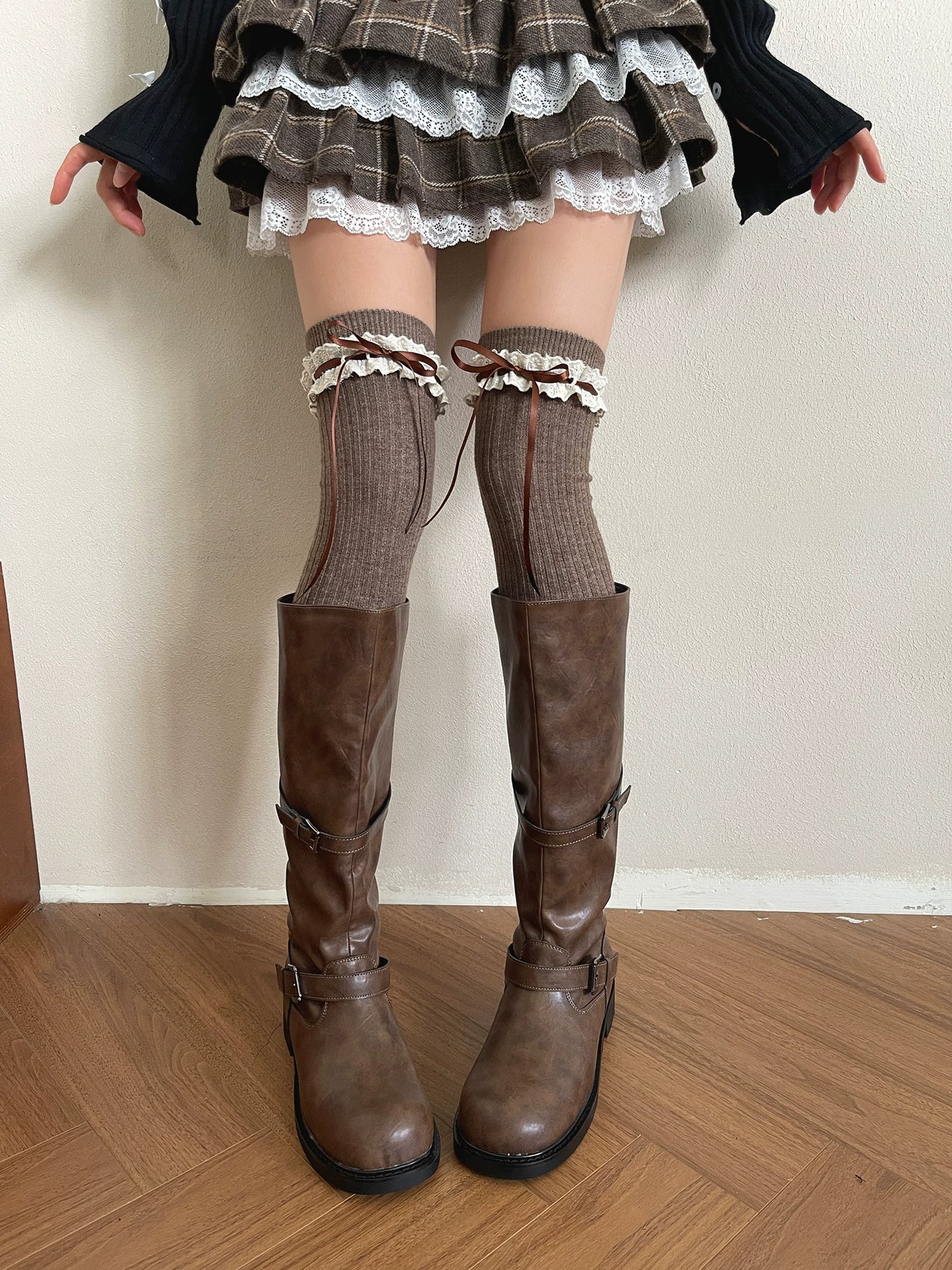 Brown over-the-knee socks with lace trim and ribbon ties styled with tall boots.