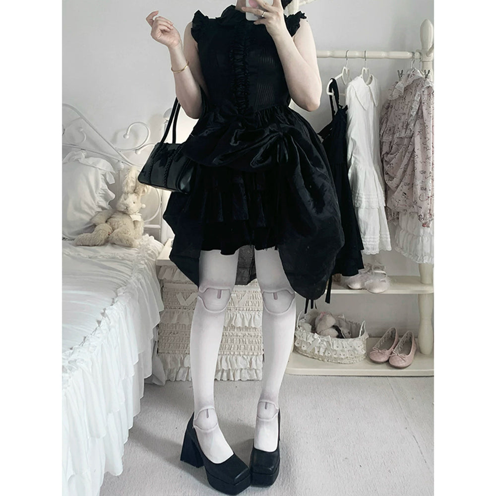 Model in a black frilled dress wearing pale tights and black platform shoes