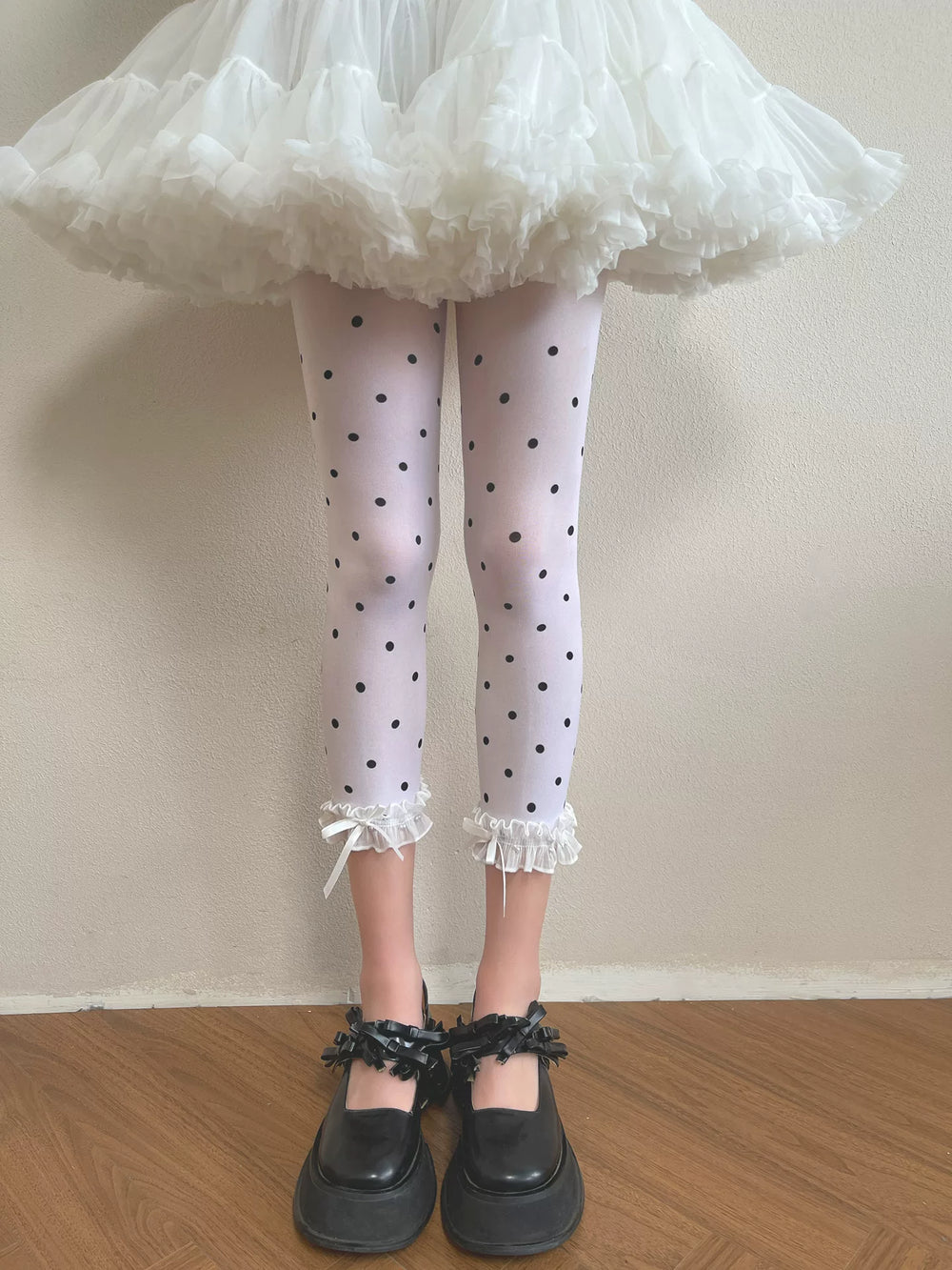White black-polka-dot tights with ruffle cuffs worn under a white ruffled skirt.