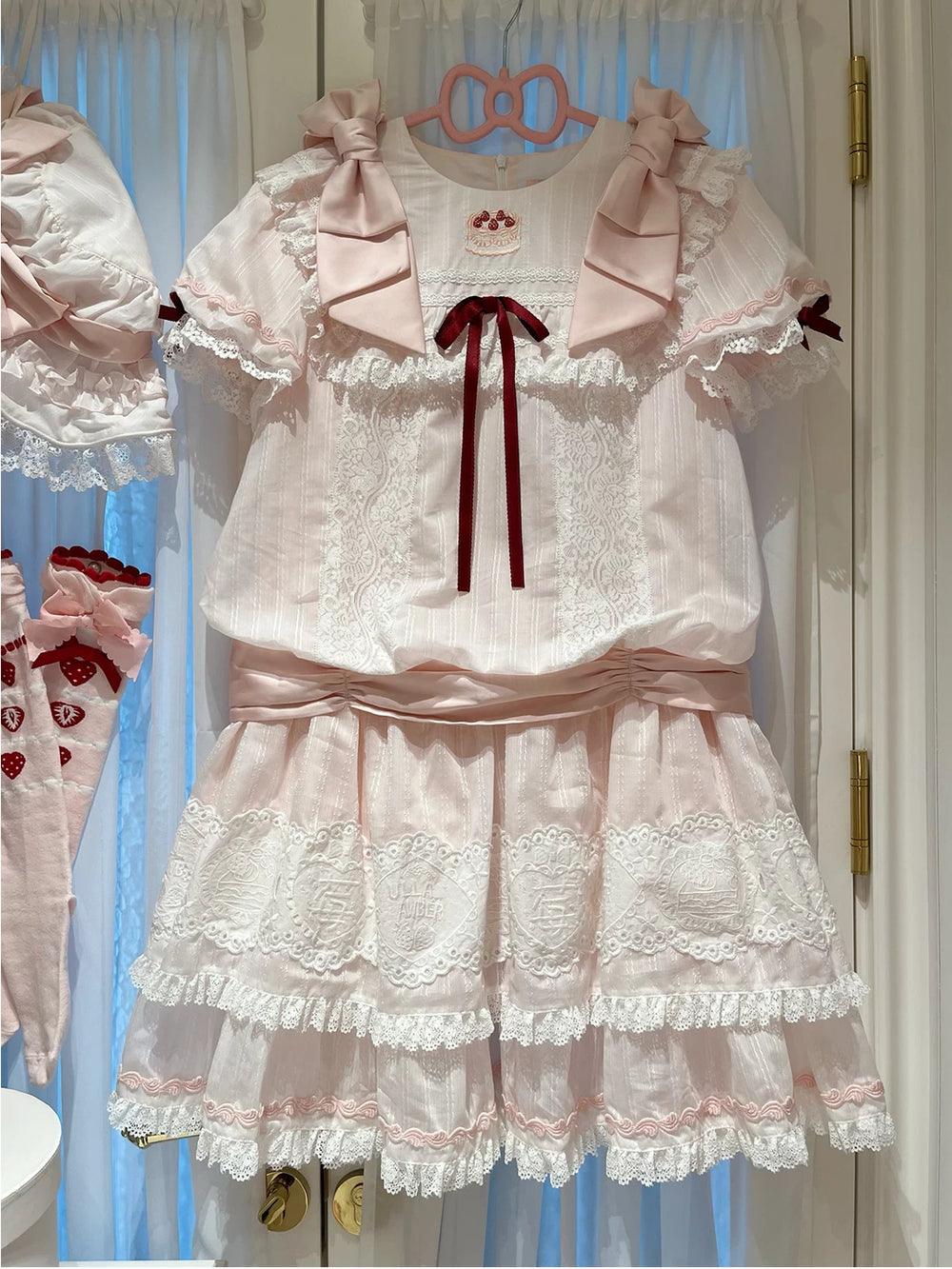 Pink-and-white low-waist OP dress with lace trim and pink bows.