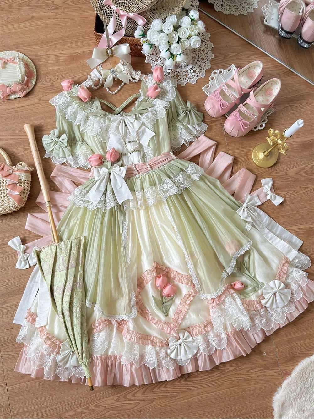 Creamy green-pink Lolita dress laid flat with floral accents, layered lace, ruffles and ribbon bows.