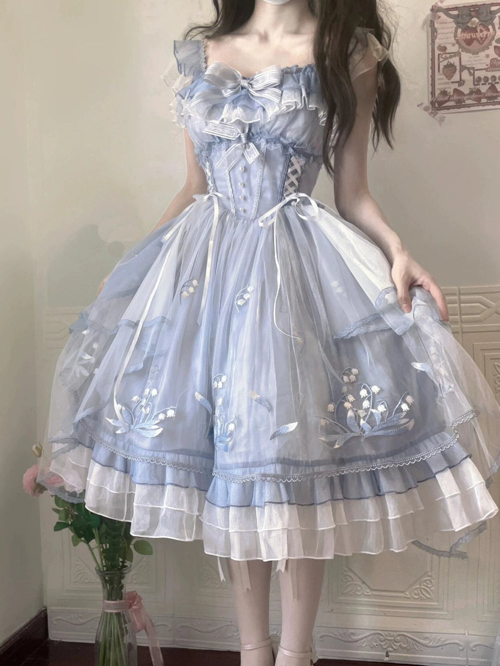 Blue embroidered Lolita dress with layered skirt and bow details worn by a model.