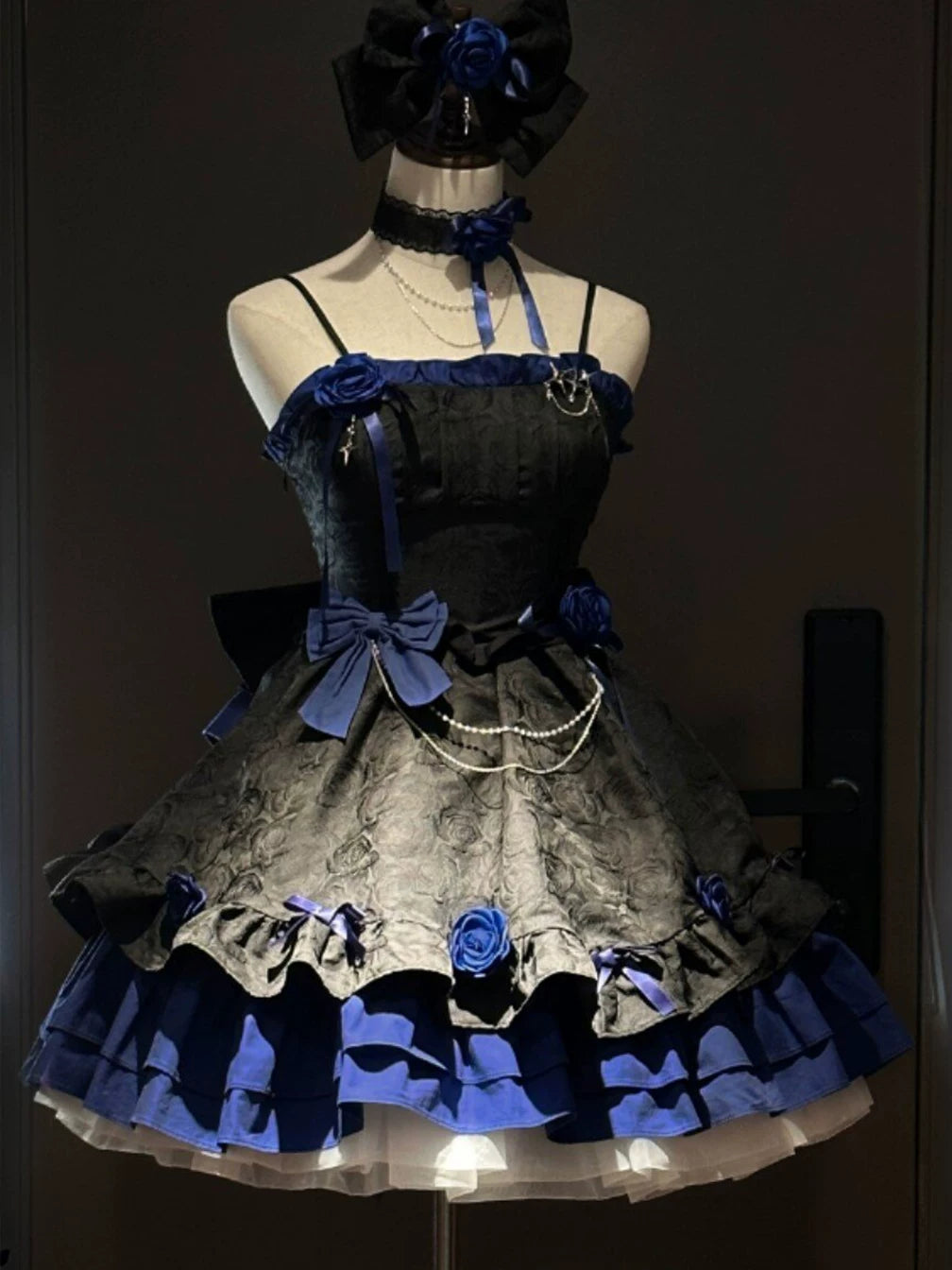 Black and blue Gothic JSK dress with blue roses and tiered ruffles on a mannequin.