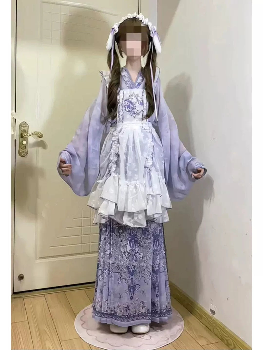 Close-up of white ruffled apron and light lavender outer robe with blue floral embroidery