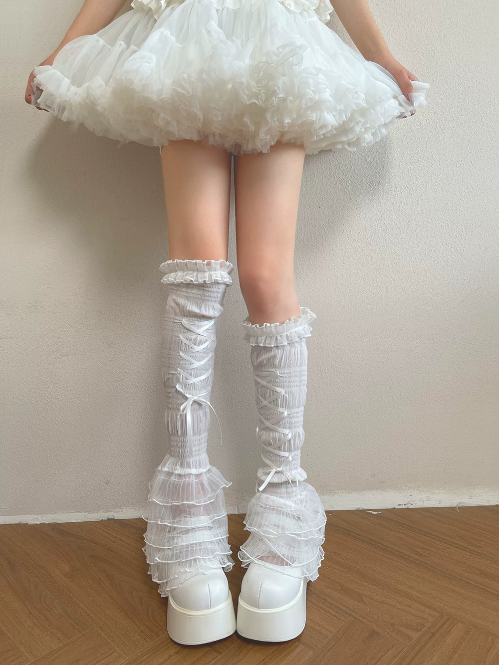 Modelled white long lace sock covers with layered ruffles and ribbon lacing
