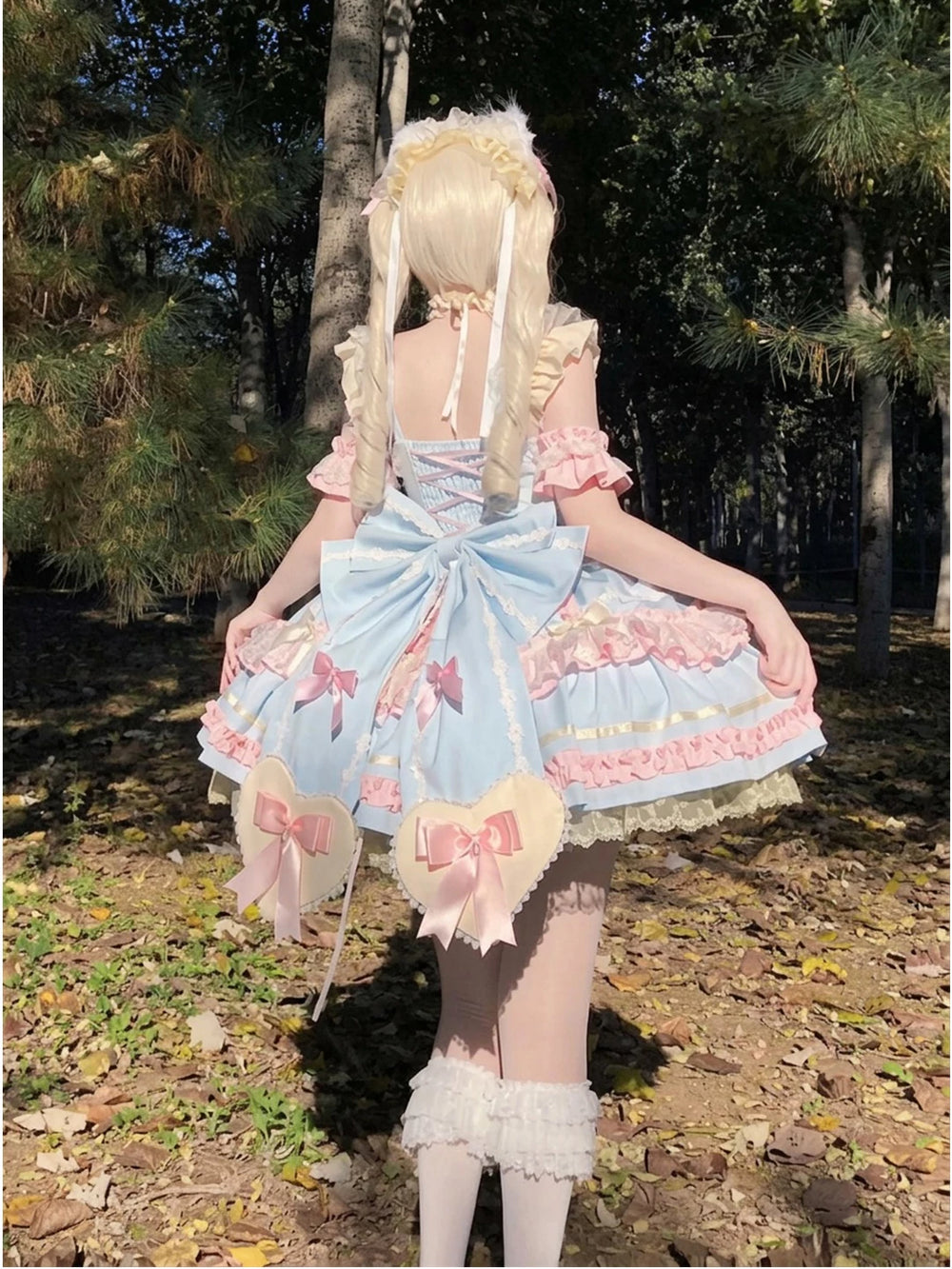 Blue-and-pink Lolita dress with bows and layered ruffles shown in an outdoor coordinate.