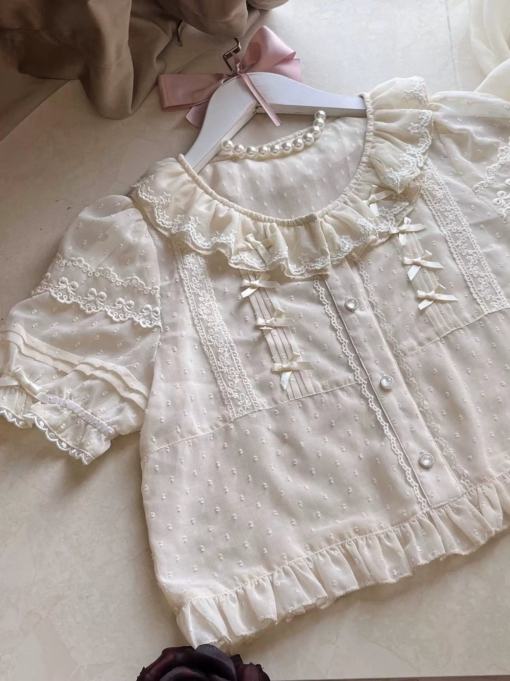White embroidered-dot Lolita blouse with lace ruffles, ribbon ties and layered flutter sleeves.
