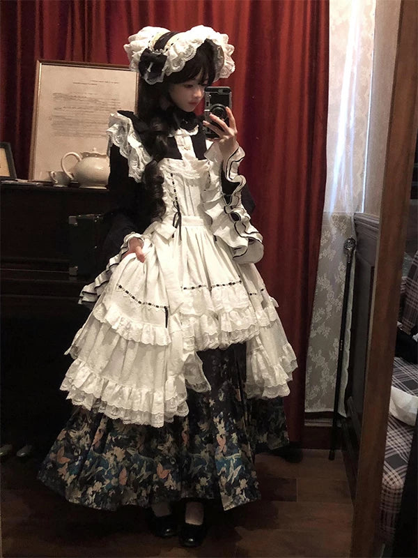 Model wearing a black cross-collar top, ruffled apron and dark floral mamian skirt.