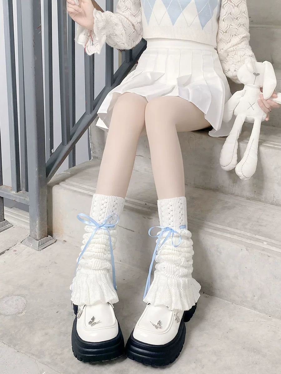 White knitted leg warmers with lace cuffs and blue ribbon ties worn over platform shoes