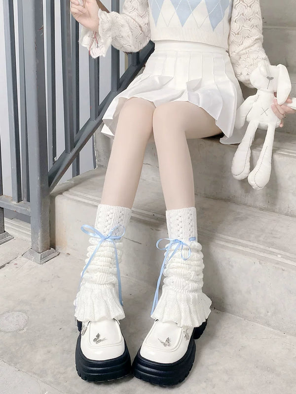 White knitted leg warmers with lace cuffs and blue ribbon ties worn over platform shoes