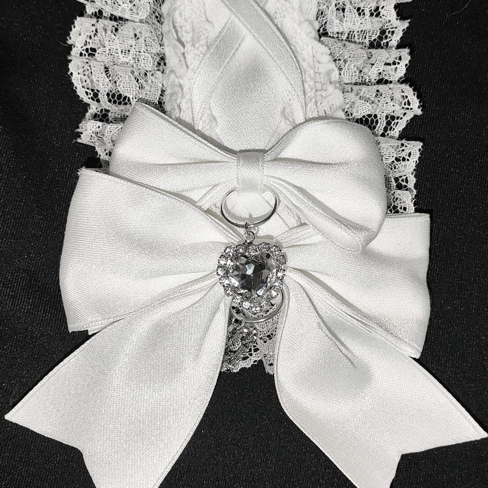 White ribbon hair accessory with a matte rhinestone heart and lace edging.