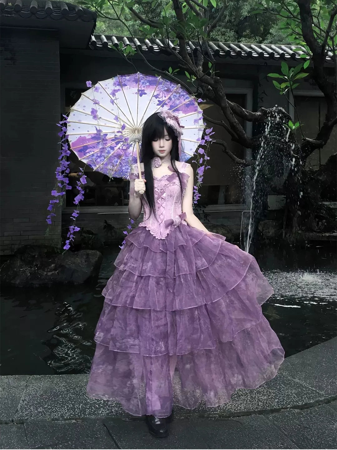 Purple long-length Lolita dress with tiered ruffles styled beside a floral parasol.