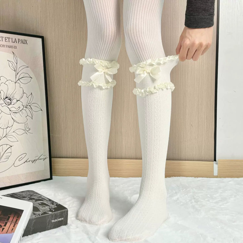 Ivory heart-pattern mid-calf socks with ruffled bow cuffs laid flat on a white surface