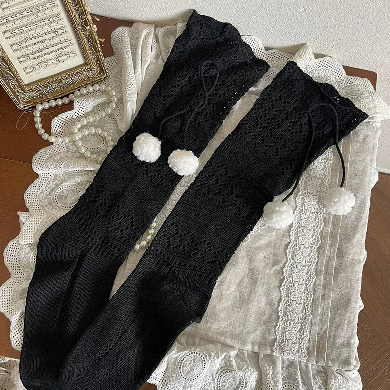 Ivory openwork slouch socks with pom-pom ties worn over white tights