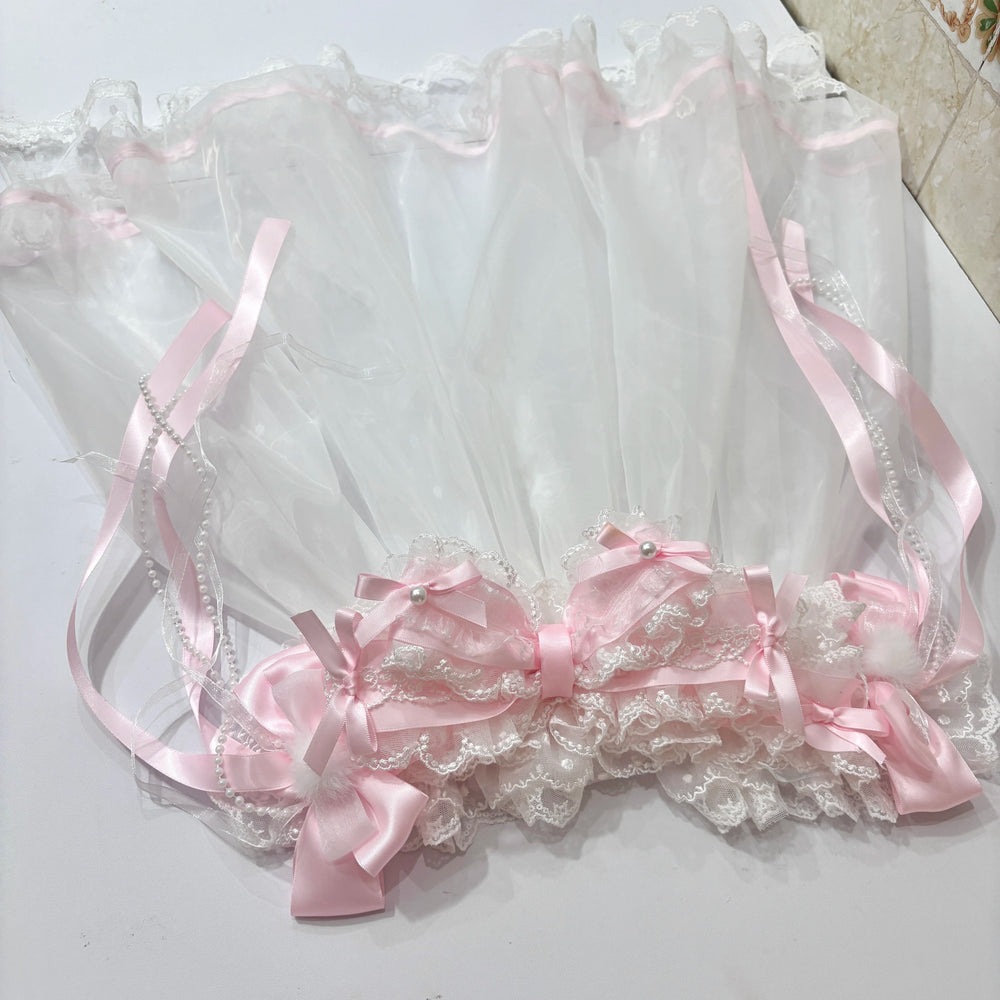 Pink-and-white lace headband and veil with ribbon bows and pearl accents laid flat.