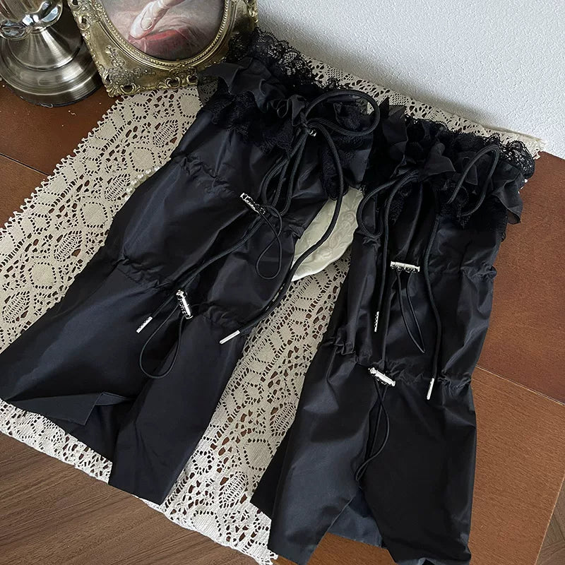 Black layered hosiery with lace ruffles, tulle knots, and glossy platform shoes beneath a black skirt.