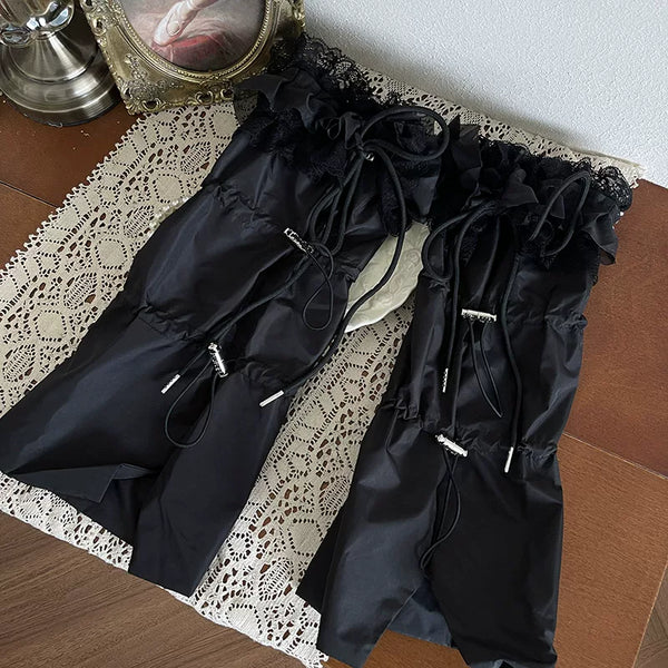 Black layered hosiery with lace ruffles, tulle knots, and glossy platform shoes beneath a black skirt.