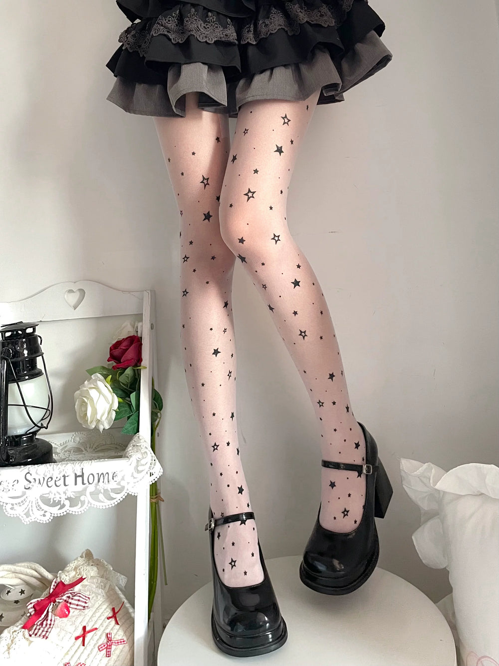 Sheer tights with scattered black stars worn with a black ruffled skirt and Mary Jane shoes.