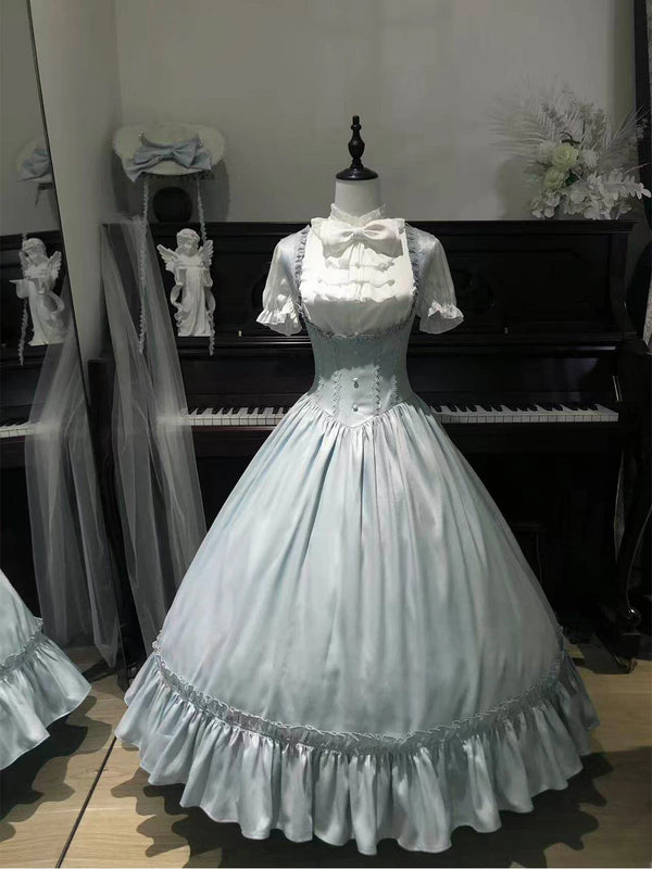 White blouse and pale blue long suspender dress displayed on a mannequin before a piano.