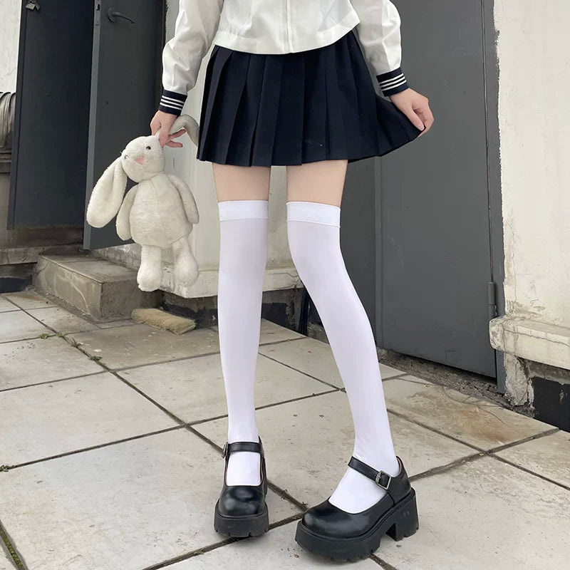 Black over-the-knee socks styled with a pleated skirt and black Mary Jane shoes