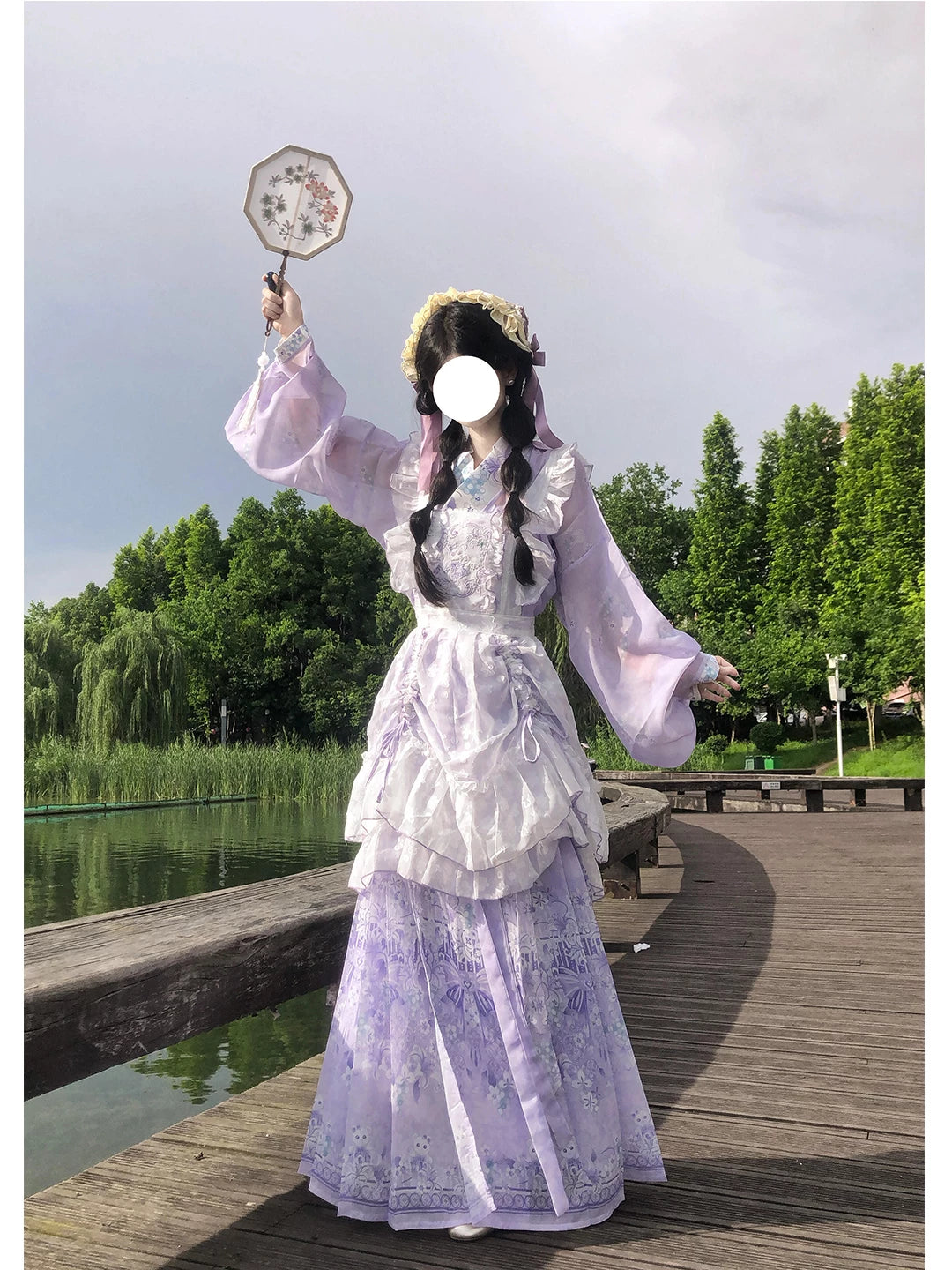 Creamy purple Hanfu-inspired layered skirt set with embroidered panels photographed beside a lakeside.