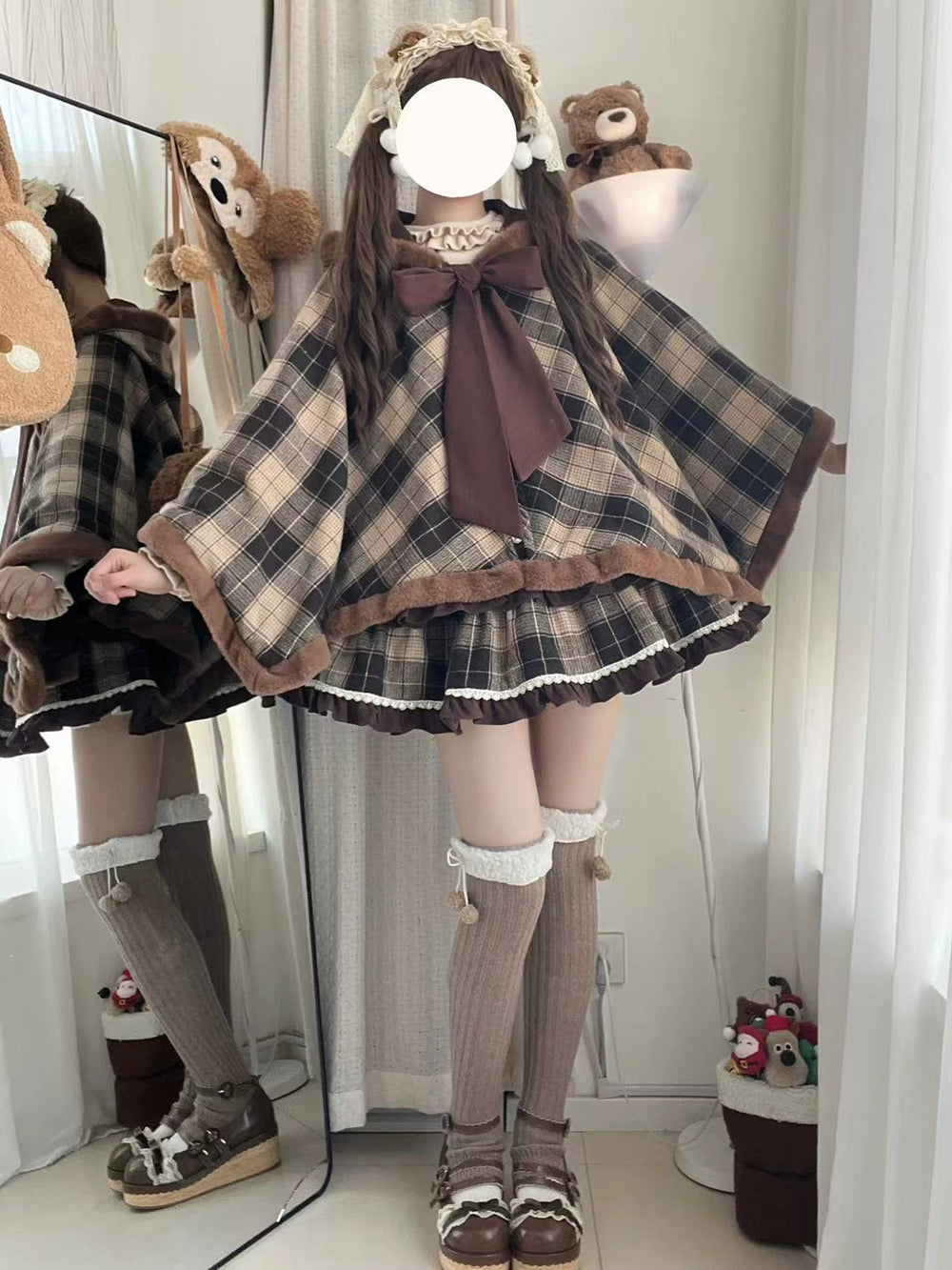 Brown plaid cape with brown trim and a large front bow shown on a model.