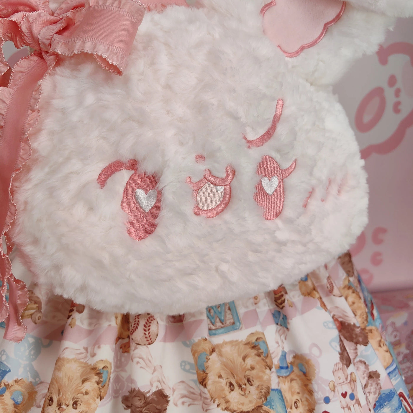 White plush rabbit backpack with long ears and pink ribbon, shown on a mannequin.