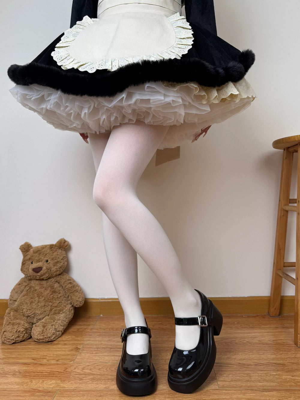 White 100D pantyhose styled with a black ruffled skirt and black Mary Jane shoes.