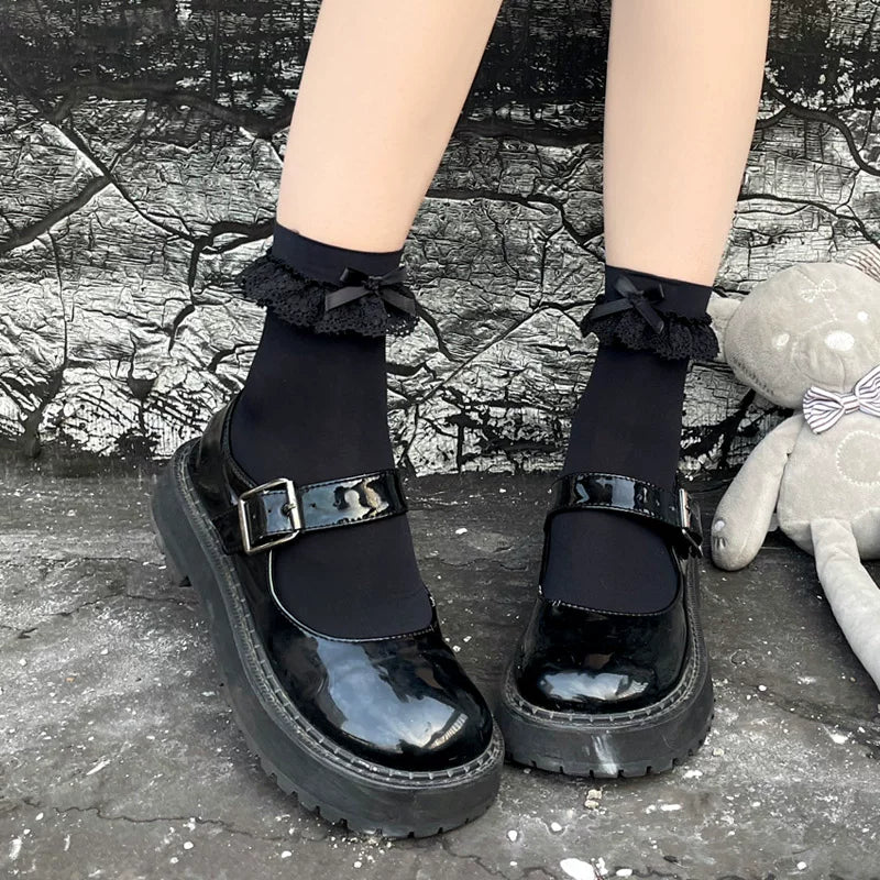 Black and white mid-calf socks with lace cuffs and bows shown with platform Mary Jane shoes.