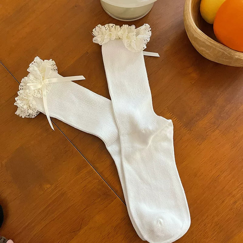 Scrunched mid-calf socks with ruffled cuffs and ribbon bows styled with platform shoes.