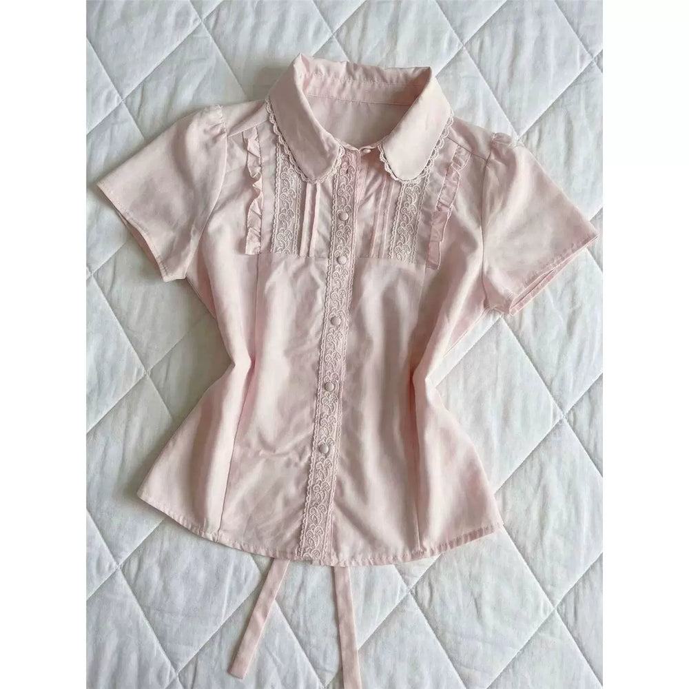 Pink short-sleeve blouse with a rounded lace-trimmed collar and front lace panels laid flat.