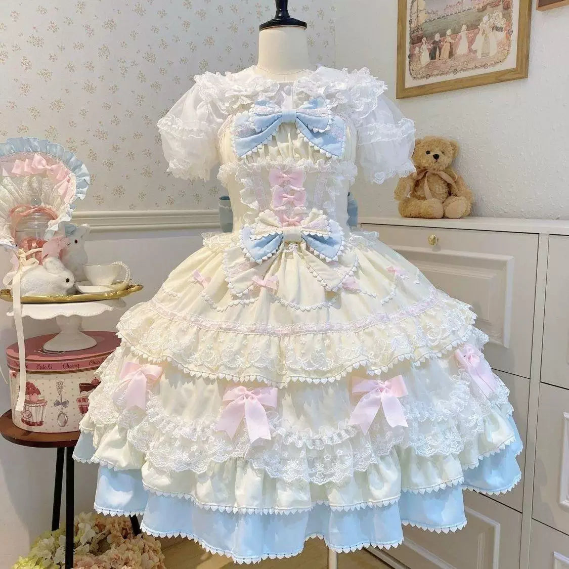 Pastel pink JSK dress with tiered ruffles and large bows displayed on a mannequin.