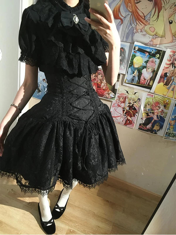 Black lace blouse-and-skirt set with a bib and laced waist shown in a mirror.