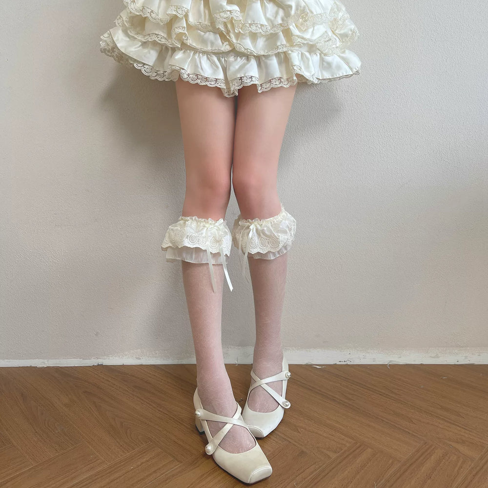 White sheer mid-calf socks with embroidered lace bow cuffs worn with cream Mary Jane shoes.
