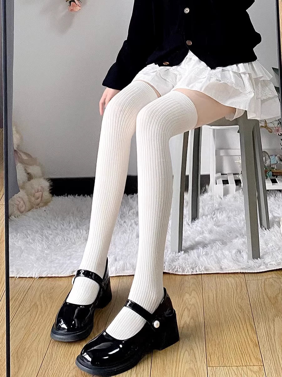 Floral Milk Cat vertical-stripe socks styled with a black cardigan, white layers, and glossy black Mary Jane shoes
