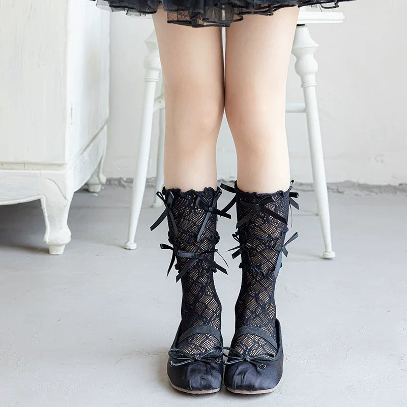 Model wearing black mesh mid-calf socks with lace panels and multiple ribbon ties.