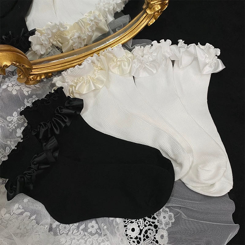 White and black ruffled lace socks arranged beside a gold mirror
