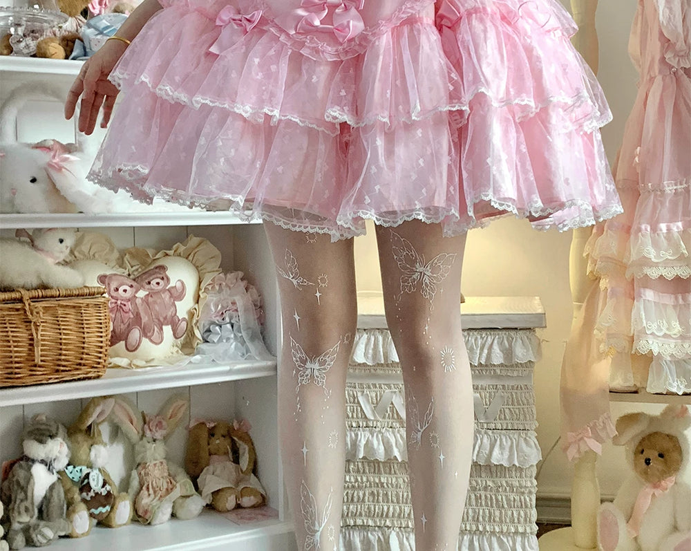 White printed pantyhose with butterfly, star and radiant motifs beneath a pink skirt