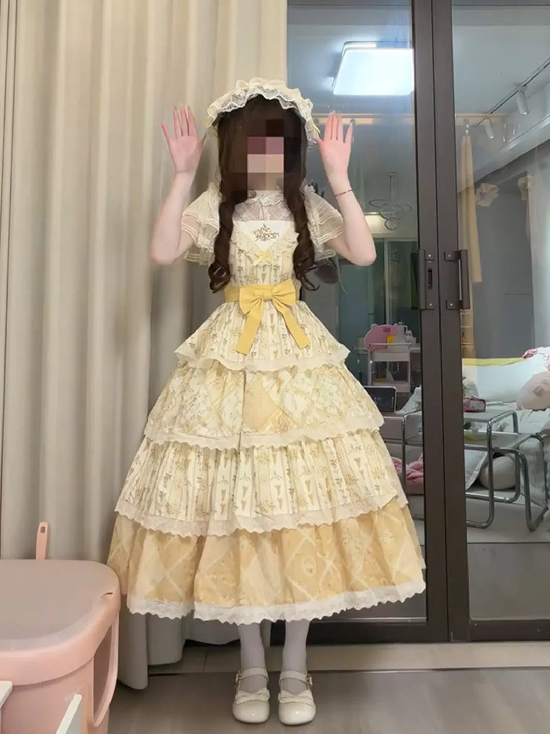 Yellow tiered JSK dress with printed panels, lace edging and a waist bow shown on a model.