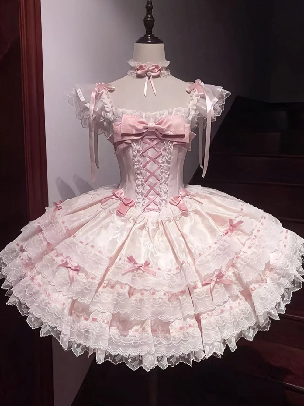 Pink balletcore Lolita dress with corset lacing and tiered skirt displayed on a mannequin
