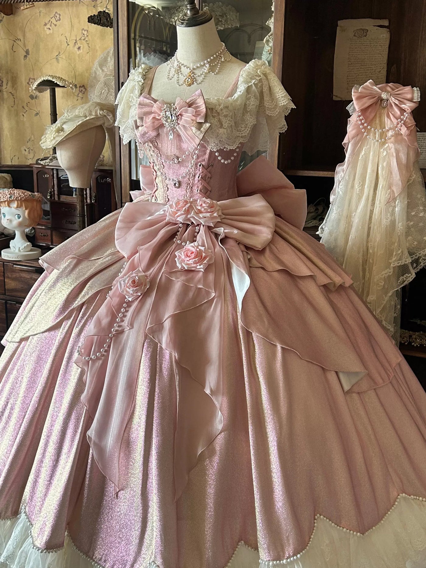 Pink lolita formal gown with corset lacing, waist bow, and fabric roses displayed on a mannequin