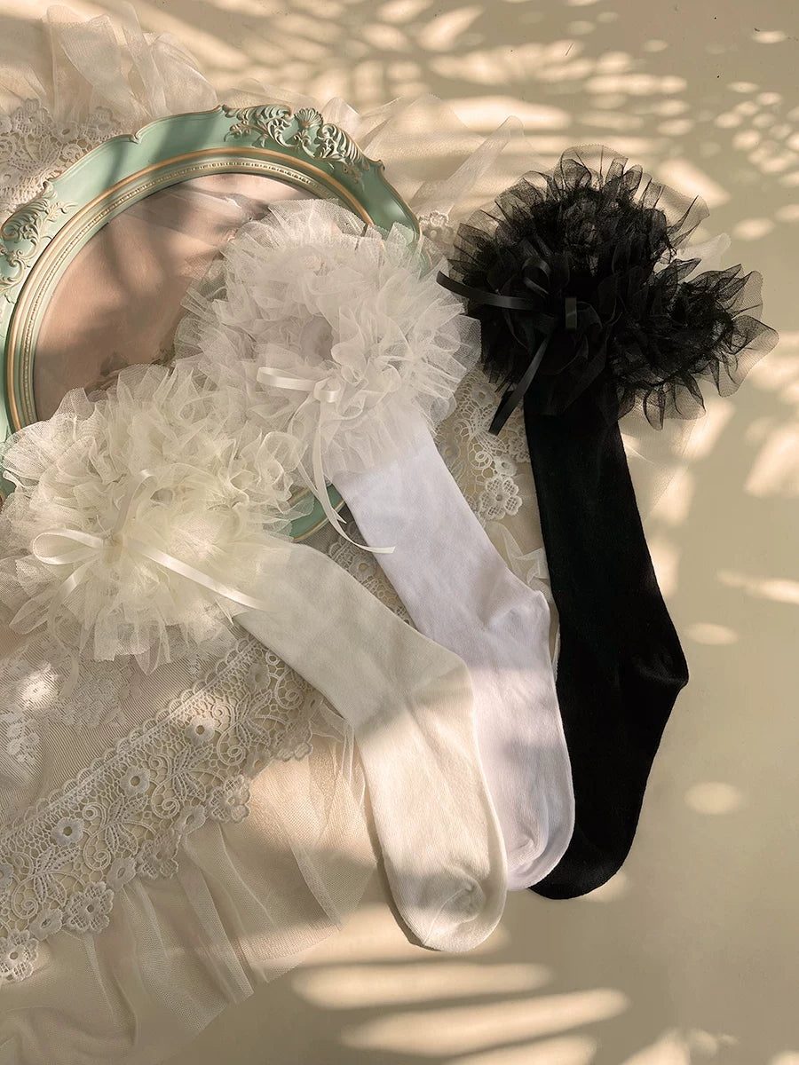 White ruffled mid-calf socks with floral lace cuffs styled with black Mary Jane shoes.