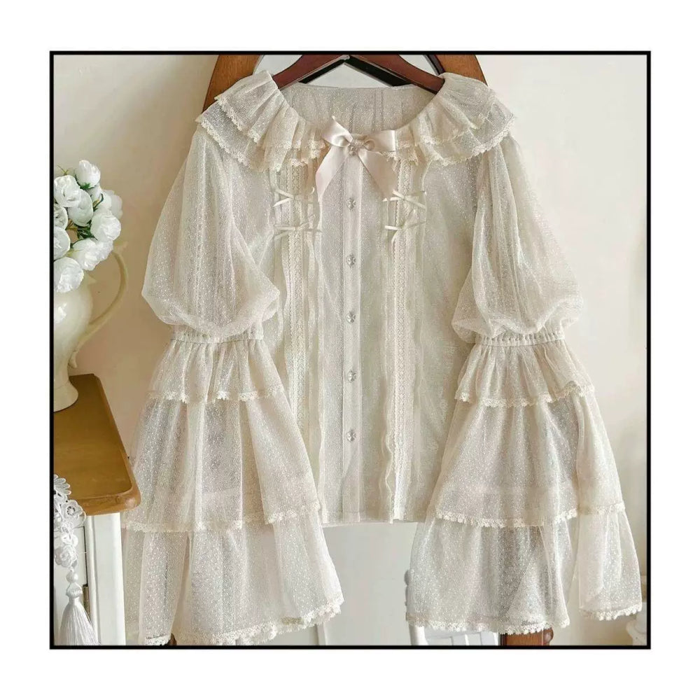 White mesh Lolita blouse on a hanger with a ruffled collar, bow, buttons and tiered sleeves.