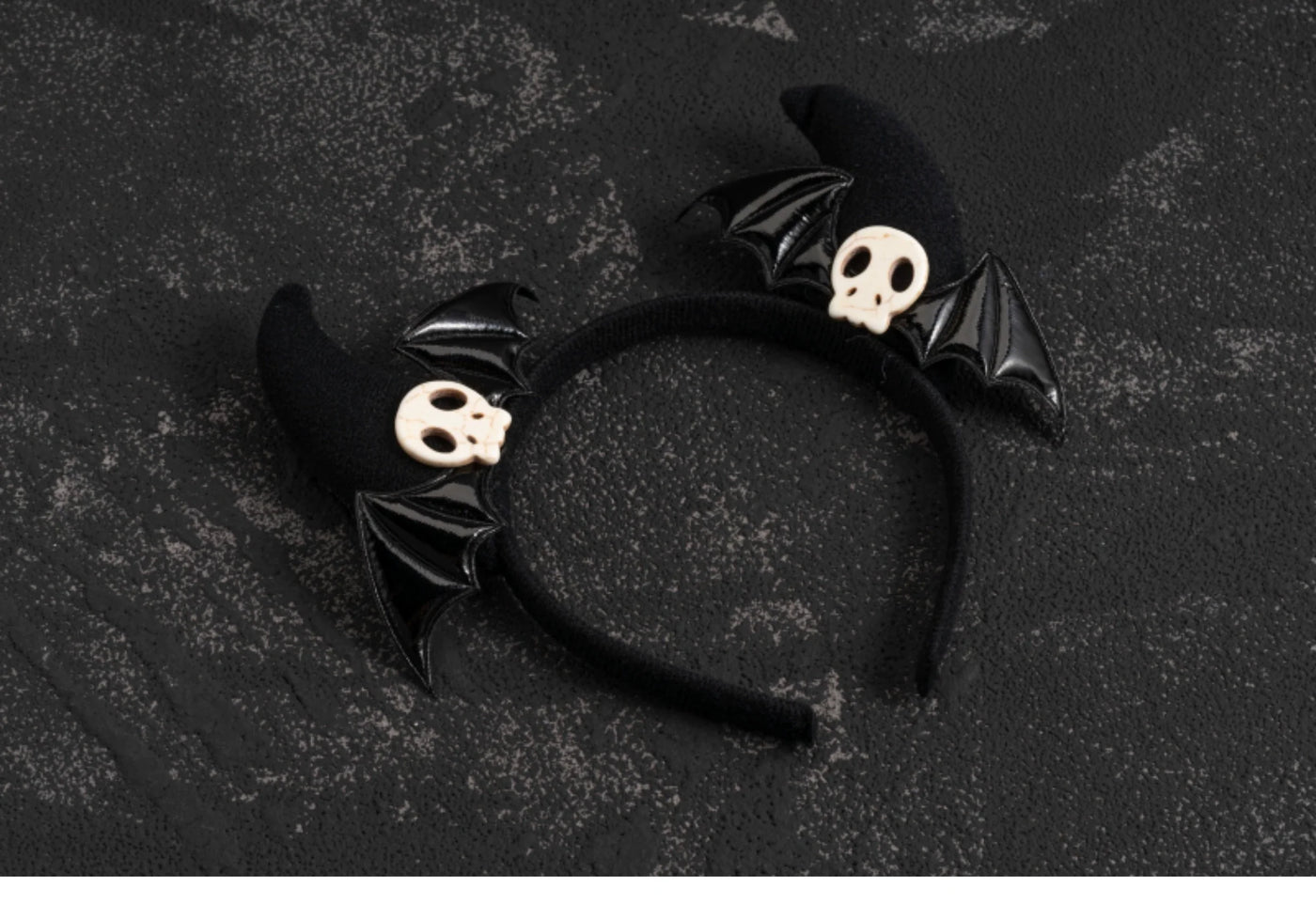 Pair of red-and-black plaid hair clips with skull charms and black cross charms on a dark textured background.