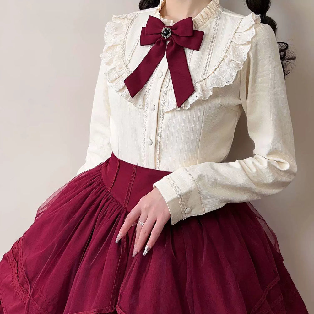 Ecru long-sleeve blouse with a broad ruffled lace collar, button front and lace-trimmed cuffs.